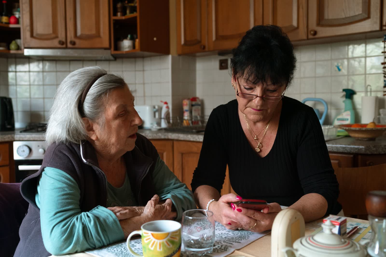 A caregiver and an older woman sitting together at her kitchen table
